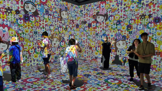 Customers take pictures at the media art section of girl group NewJeans’ pop-up store held at the Line Friends Square in Shibuya, Japan, on June 26. [YOON SO-YEON]