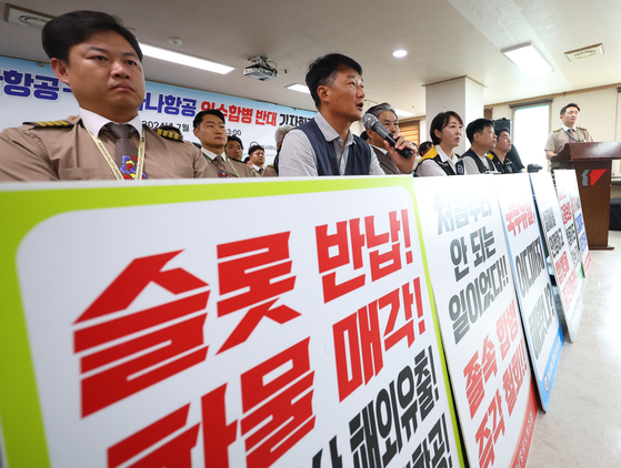 Unionized Asiana Airlines workers hold a press conference opposing their employer's merger with Korean Air Lines in central Seoul on Thursday. [YONHAP]