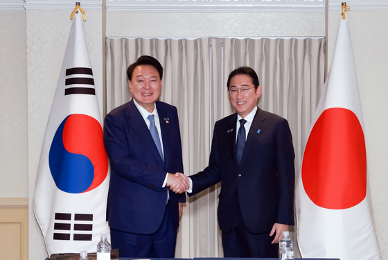 President Yoon Suk Yeol, left, and Japanese Prime Minister Fumio Kishida shake hands during a bilateral meeting on the sidelines of the North Atlantic Treaty Organization (NATO) summit in Washington on Wednesday. [YONHAP] 