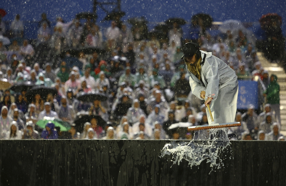 A worker sweeps rain water at the Trocadero during the opening ceremony of the 2024 Paris Olympics.  [AP/YONHAP]