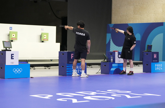 Korea's Lee Won-ho, left, and Oh Ye-jin are in action during the mixed team 10-meter air pistol bronze-medal match at the Paris Olympics on Tuesday in Chateauroux, France. [REUTERS/YONHAP]