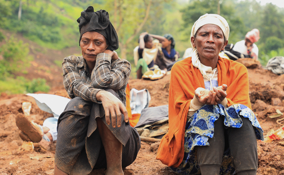 Zeritu Zekarias, 43, sits with her neighbor as her husband and relatives dig in search of the missing son at the site of a landslide of July 22 that buried people in the Gofa zone of southern Ethiopia on Monday. [REUTERS/YONHAP]