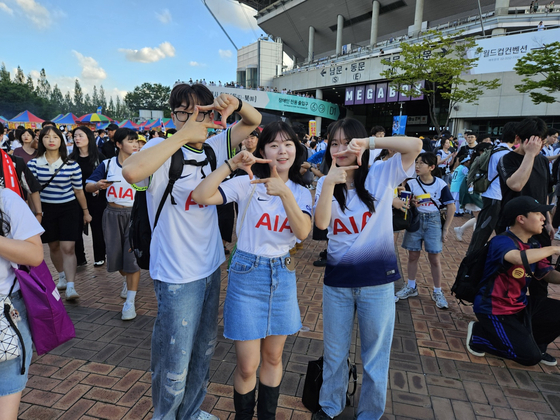 Football fans wearing Tottenham Hotspur jerseys pose with Son Heung-min's iconic celebration at Seoul World Cup Stadium in western Seoul on Wednesday ahead of a Coupang Play Series match between Spurs and Team K League. [PAIK JI-HWAN]