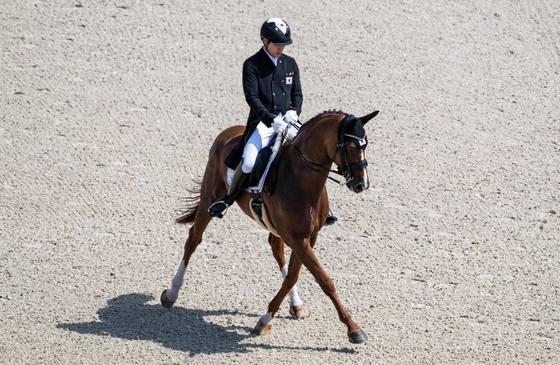 Korea's Hwang Young-shik with horse Delmonte 7 competes in the equestrian dressage individual grand prix during the Paris Olympics at the Chateau de Versailles in Versailles, France on Tuesday. [AFP/YONHAP]