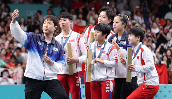 Olympic table tennis players from South and North Korea, along with Chinese players, pose together to take a selfie on the podium using the Samsung Galaxy Z Flip 6 during the Paris 2024 Olympics on July 30. [YONHAP]