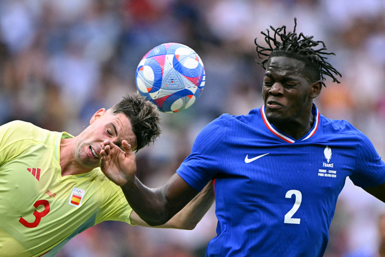 Spaish defender Juan Miranda heads the ball next to French defender Castello Lukeba in the men's gold medal football match in Paris on Friday.  [AFP/YONHAP]