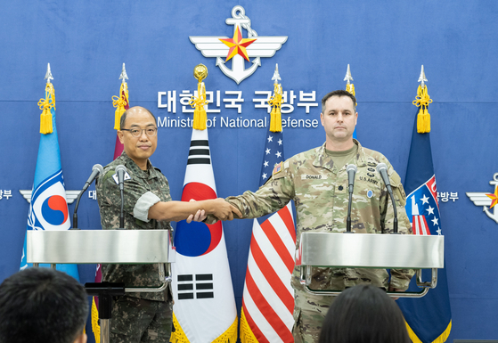 Joint Chiefs of Staff spokesman Col. Lee Sung-jun, left, and United States Forces Korea spokesman Col. Ryan Donald shake hands at a joint press briefing on the Ulchi Freedom Shield exercise at the Defense Ministry in Seoul on Monday. [JOINT CHIEFS OF STAFF]
