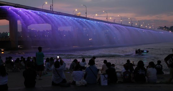 People watch the water fountain from Banpo Bridge as tropical nights continued on Thursday. [YONHAP] 