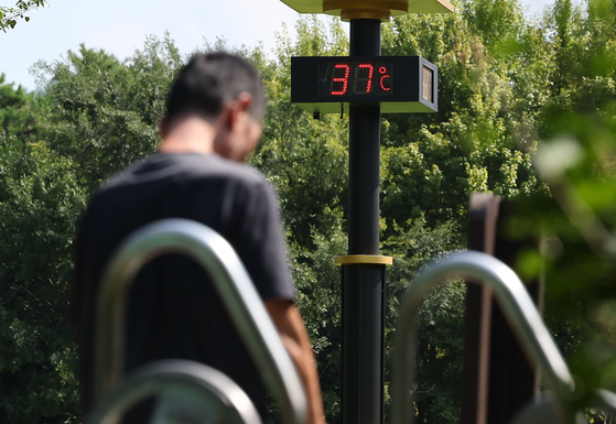 A person swelters in front of a thermometer indicating a daily temperature of 37 degrees Celsius (98.6 degrees Fahrenheit) in Seocho District, southern Seou,l on Monday. [YONHAP] 