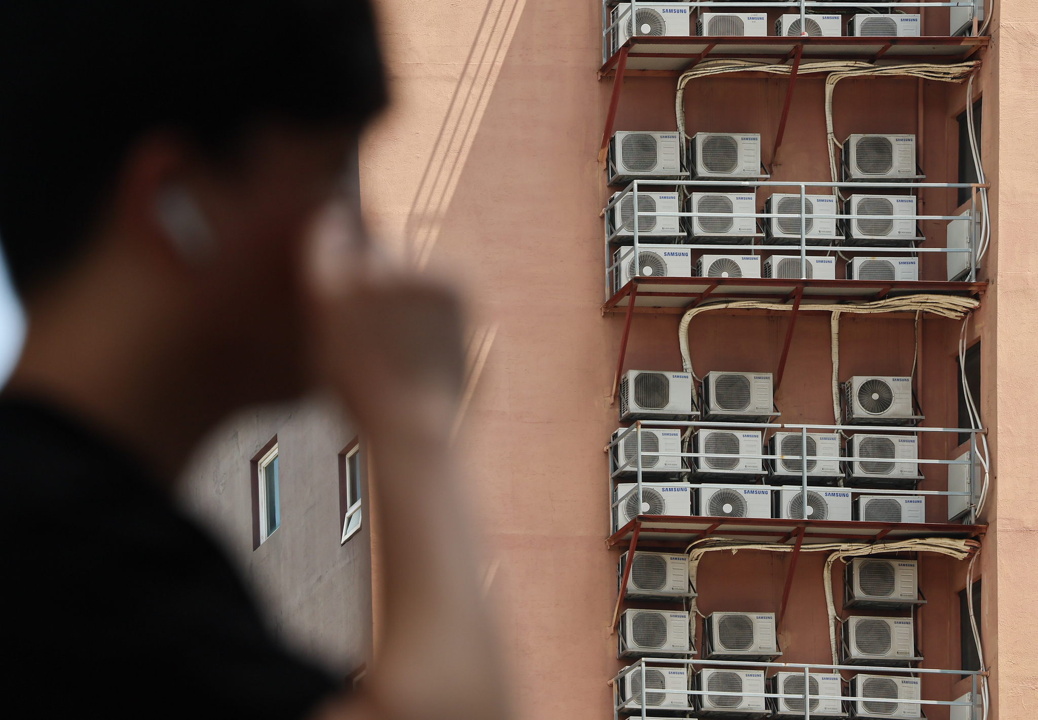 Condenser units connected to indoor air conditioners operate outside of a building in downtown Seoul last Wednesday. [NEWS1]