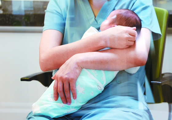 A nurse holds a newborn at a postpartum center in Yanggu County, Gangwon, on Dec. 4, 2023. [YONHAP]