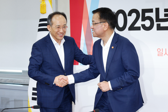Finance Minister Choi Sang-mok, right, shakes hands with People Power Party floor leader Rep. Choo Kyung-ho during a policy consultation meeting held at the National Assembly in western Seoul on Tuesday. [NEWS1]
