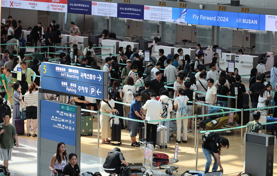 Travelers wait in line at airline counters at Incheon International Airport. [YONHAP]