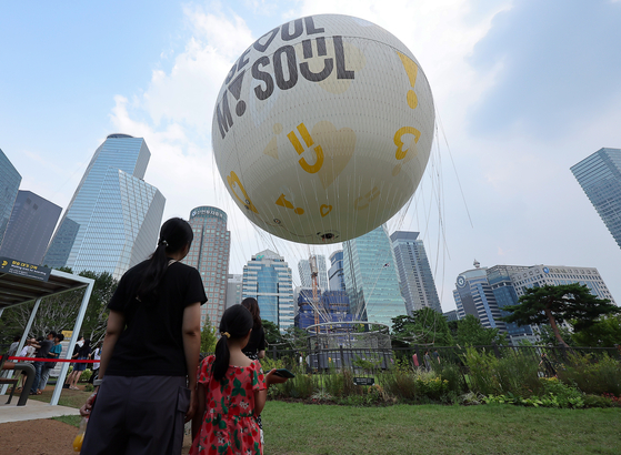 Visitors watch a moon-shaped tethered balloon ride, dubbed ″Seouldal,″ getting ready to welcome passengers on the ground in Yeouido Park in western Seoul on Sunday. "Dal" means moon in Korean. The Seoul Metropolitan Government on the same day announced that the balloon had its official maiden flight last Friday in Yeouido Park in western Seoul. The ride is available every Tuesday to Sunday between 12 p.m. and 10 p.m. [NEWS1] 