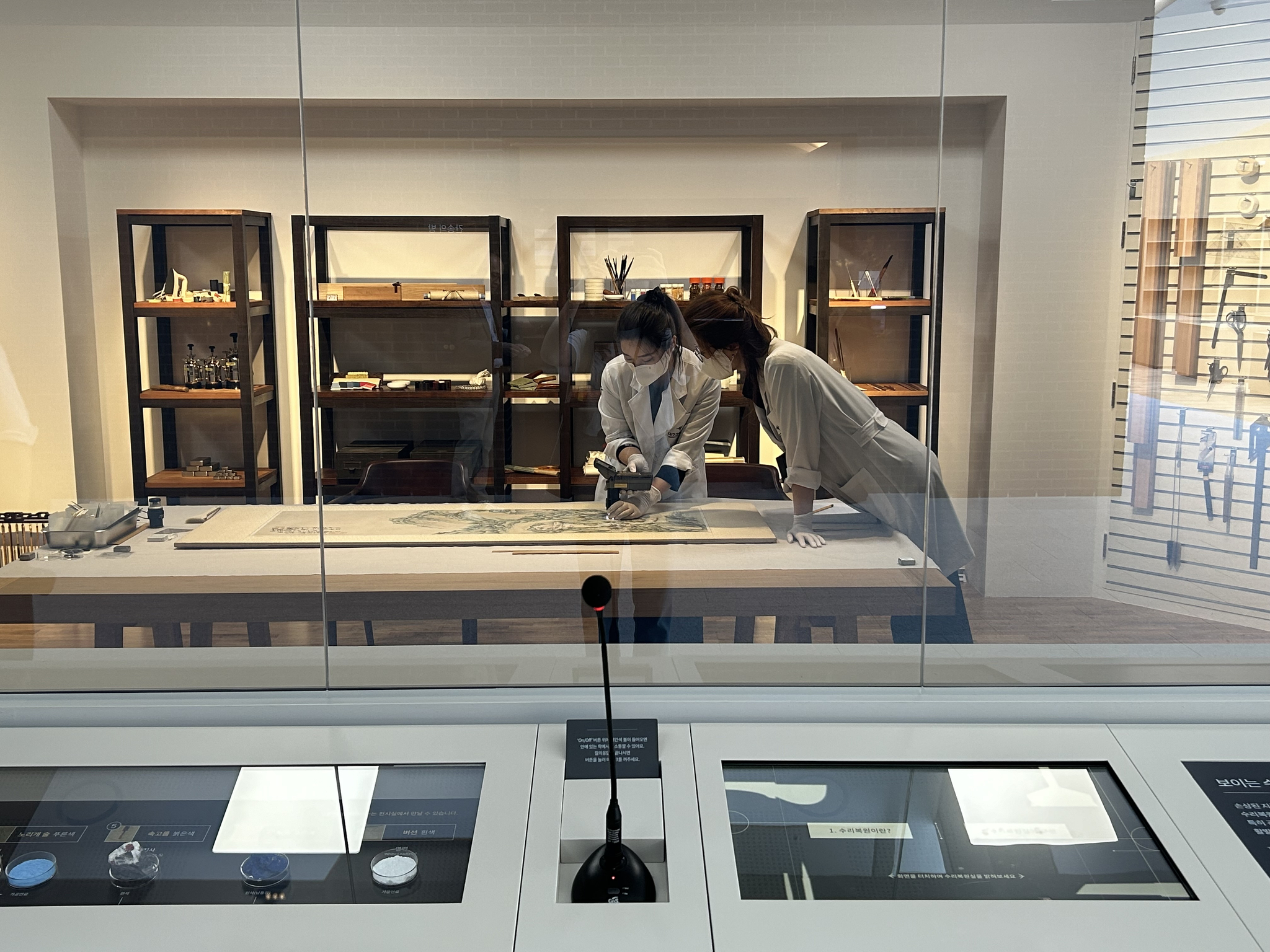 Experts fix damaged artifacts and artworks in the Kansong Art Museum Daegu's Open Conservation Studio on Tuesday. Visitors are allowed to interact with the conservators via the microphone on set. [SHIN MIN-HEE]