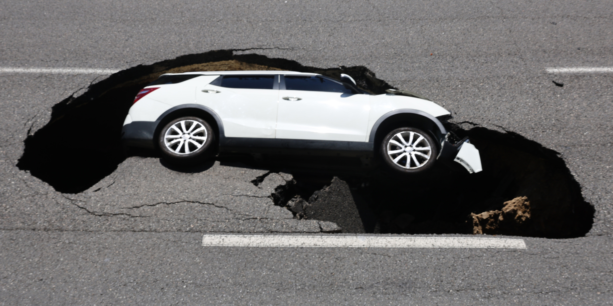A Tivoli SUV is swallowed up by a sinkhole that appeared on a road in Seodaemun District, western Seoul on Thursday morning. [YONHAP]  