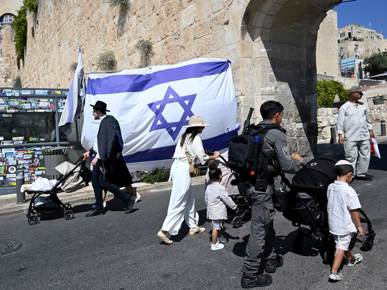 Israelis walk past a national flag at the Dung Gate of the Old City of Jerusalem, which leads to the southern wall of the Temple Mount and the Western Wall in Jerusalem on Thursday. [UPI/YONHAP]