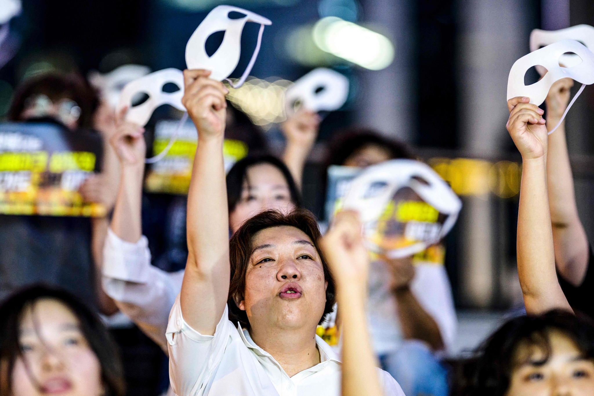 Activists hold masks and shout slogans during a protest against deepfake porn in Gangnam District, southern Seoul, on Friday. [AFP/YONHAP]