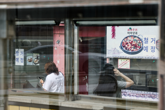 People pass a recently closed store in Seodaemun District, western Seoul, on Sunday. [YONHAP] 