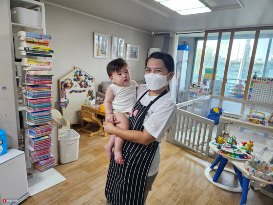 Filipino domestic caregiver Mary Grace, 36, poses for a photo with a child on Tuesday at a household where she began working under the foreign domestic caregiver scheme that launched the same day. [SEOUL METROPOLITAN GOVERNMENT]