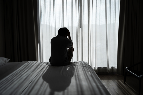 Lonely young man feeling depressed and stressed sitting in the dark bedroom. [GETTY IMAGES]