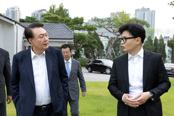 President Yoon Suk Yeol, left, and People Power Party leader Han Dong-hoon, right, walk on the lawn of the Pine Grass reception hall inside the presidential complex in Yongsan District, central Seoul, on Monday afternoon. [PRESIDENTIAL OFFICE] 