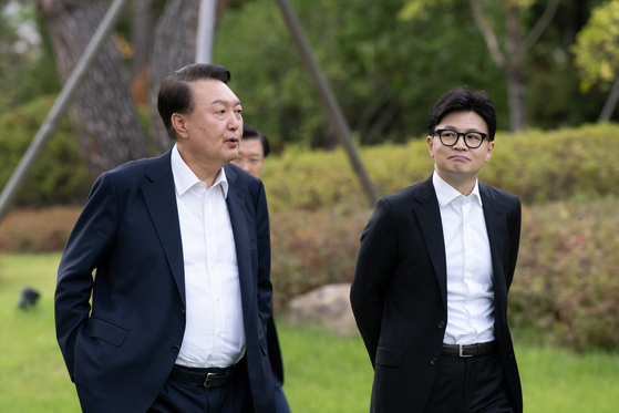 President Yoon Suk Yeol, left, and People Power Party leader Han Dong-hoon, right, walk on the lawn of the Pine Grass reception hall inside the presidential complex in Yongsan District, central Seoul, on Monday afternoon. [PRESIDENTIAL OFFICE]
