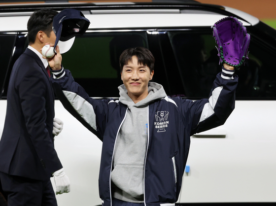 BTS member J-Hope waves to the crowd after throwing out the ceremonial first pitch before Game 2 of the Korean Series between the Kia Tigers and Samsung Lions at Gwangju-Kia Champions Field in Gwangju. [YONHAP]