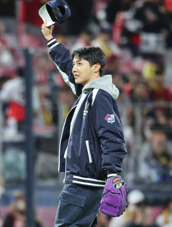 BTS member J-Hope waves to the crowd after throwing out the ceremonial first pitch before Game 2 of the Korean Series between the Kia Tigers and Samsung Lions at Gwangju-Kia Champions Field in Gwangju. [NEWS1]