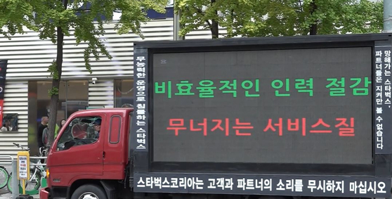 A protest truck accusing Starbucks Korea of "inefficient workforce reduction" that leads to "poor service quality" is parked in front of a Starbucks store in Changcheon-dong, western Seoul, on Monday as shown in SBS's news report. [SBS]