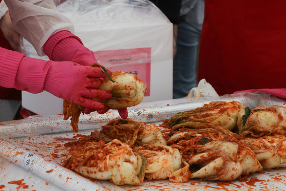 A participant makes kimchi at an event in Yeouido Park in western Seoul on Tuesday. [YONHAP]