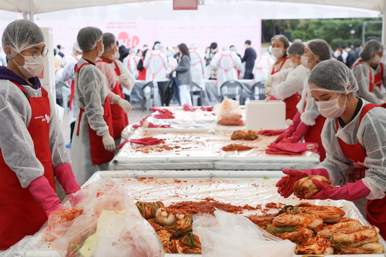 Participants make kimchi at an event in Yeouido Park in western Seoul on Tuesday. [YONHAP]