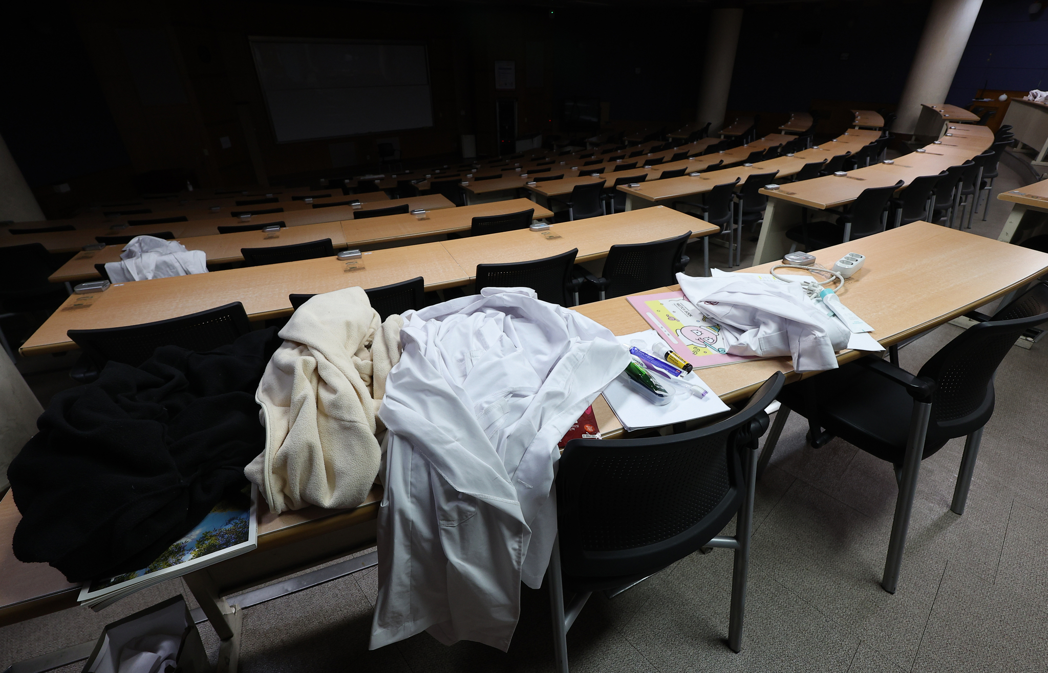 Medical gowns are laid on students' desks at a lecture hall in a medical school's building in Daegu on Wednesday. [YONHAP] 