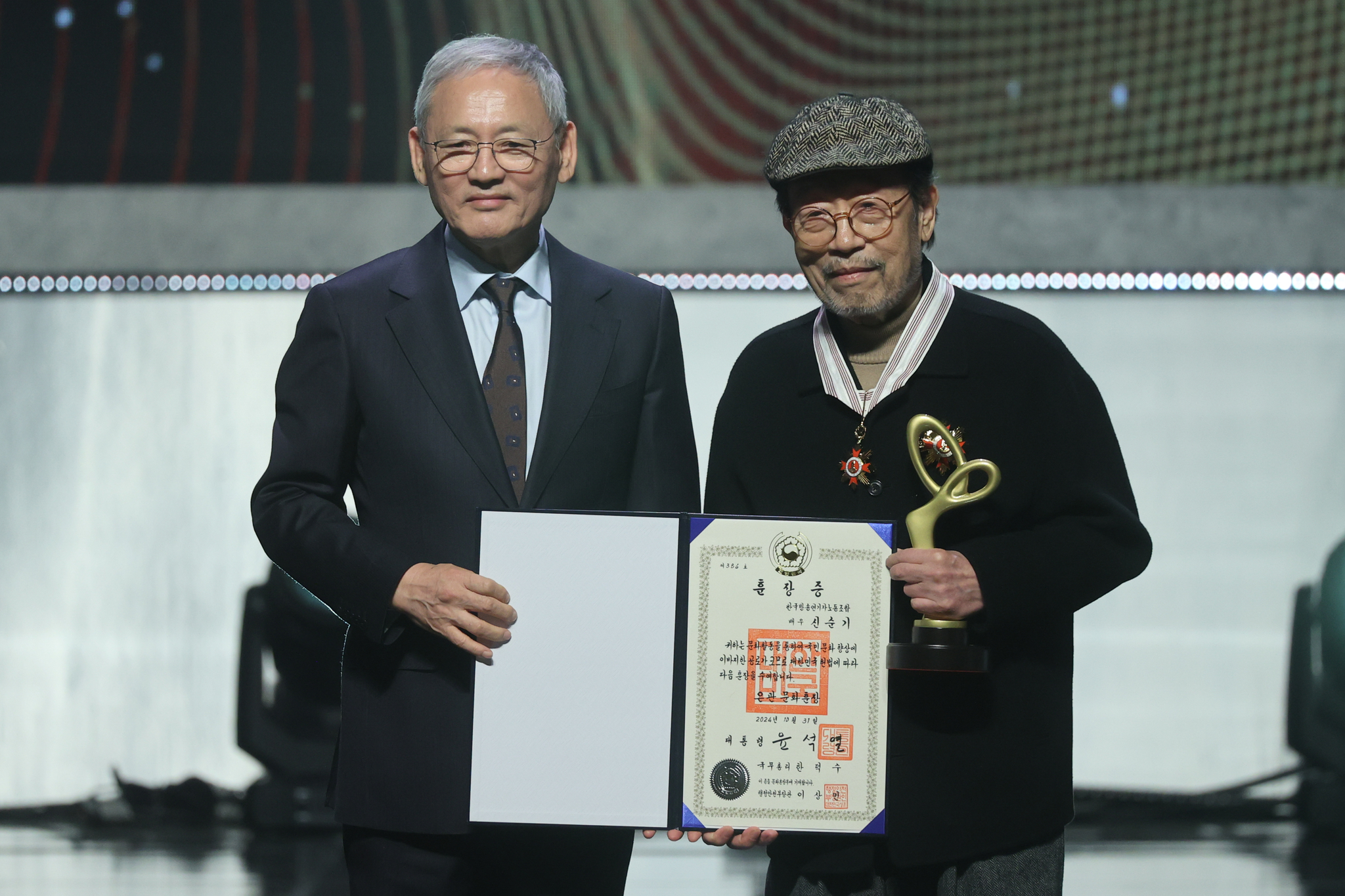Actor Shin Goo, right, poses for a photo with Culture Minister Yu In-chon after receiving the Eungwan, or silver crown, Order of Cultural Merit, this year’s highest accolade, during the Korea Popular Culture and Arts Awards held at the National Theater's Haeoreum Grand Theater in Jung District, central Seoul, on Thursday evening. [YONHAP]