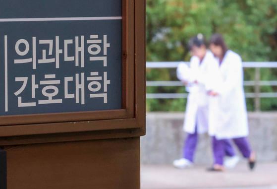 Two people in white medical gown are seen in front of a medical college building in Seoul in last month. [YONHAP] 