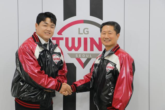 New LG Twins reliever Jang Hyun-sik, left, shakes hands with the club's CEO, Kim In-seog, in front of the team's logo at Jamsil Baseball Stadium in southern Seoul after signing a free agent contract with the Twins on Monday. [YONHAP]