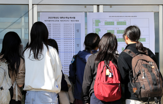 Students taking the College Scholastic Ability Test check their exam venues at a high school in Jeju on Wednesday, the day before the exam. [YONHAP] 