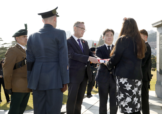 British Ambassador to Korea Colin Crooks, third from left, presents military funeral honors for rifleman Mark Foster to British Ministry of Defense detective Nicola Nash, second from right, at the United Nations Memorial Cemetery in Busan on Tuesday. Nash said she plans to deliver the honors to Foster's surviving kin upon her return to Britain. [PARK SANG-MOON]