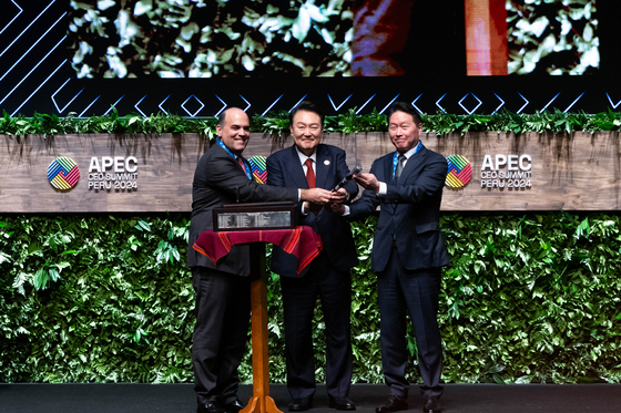 President Yoon Suk Yeol, center, and Chey Tae-won, chairman of the Korea Chamber of Commerce and Industry, right, who will chair the 2025 Gyeongju APEC CEO Summit, receive the gavel from Chairman Fernando Zavala at the APEC CEO Summit held in Lima, Peru, on Friday. [PRESIDENTIAL OFFICE] 