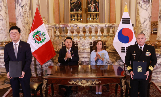 Korean President Yoon Suk Yeol, center left, and Peruvian President Dina Boluarte, center right, clap at a signing ceremony of a memorandum of understanding for the joint development of submarines for the Peruvian Navy in Lima, Peru, on Saturday. [JOINT PRESS CORPS]