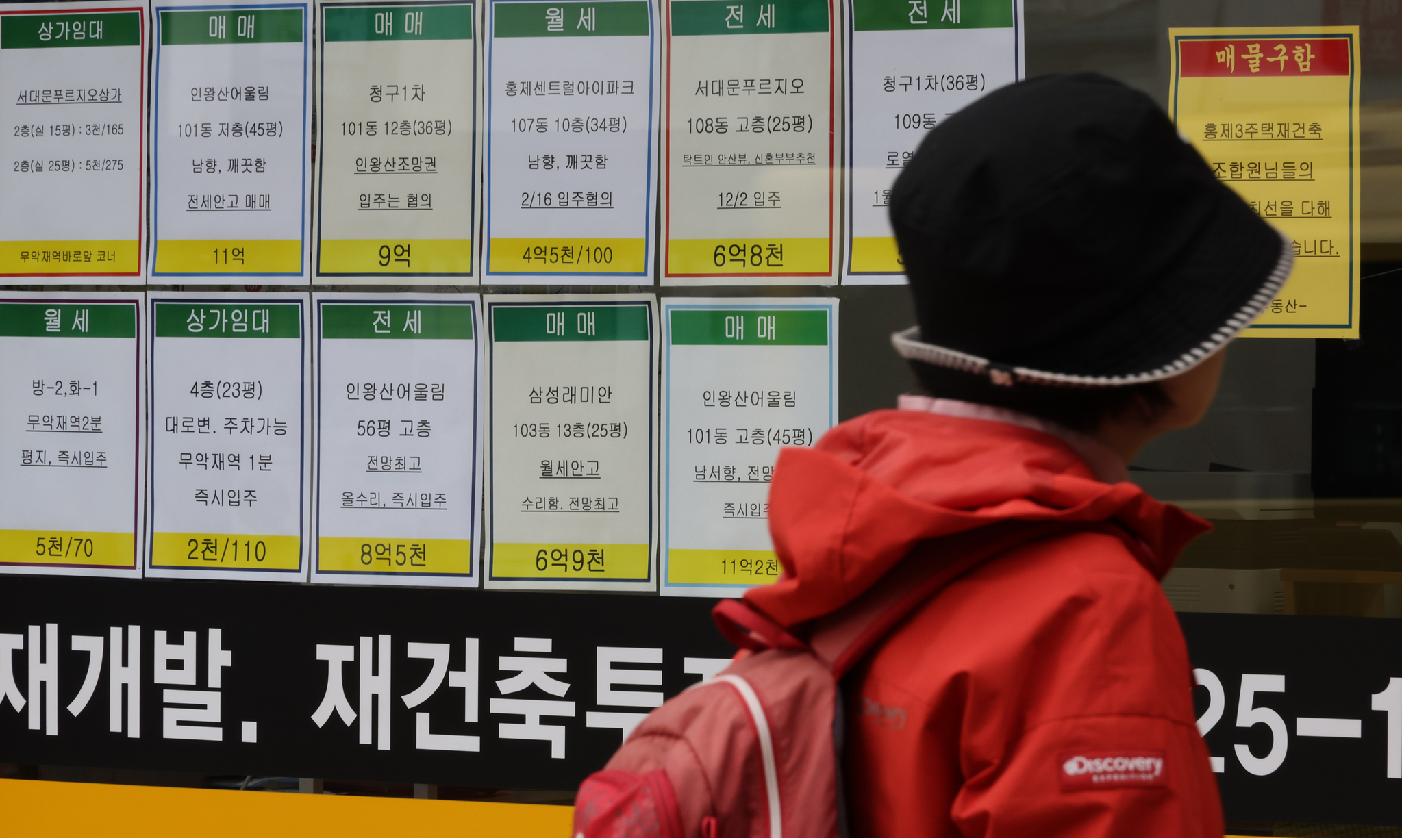 A person looks at signs about a bank's loan programs on the exterior of a lender in Seoul. [YONHAP] 
