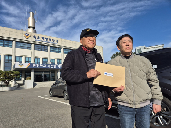 Choi Seong Ryong, left, representative of a group of South Korean relatives of people abducted to the North, and Park Sang-hak, representative of a North Korean defectors' group, display an envelope containing anti-Pyongyang leaflets in front of the Sokcho Coast Guard Station in Gangwon on Tuesday. [NEWS1]