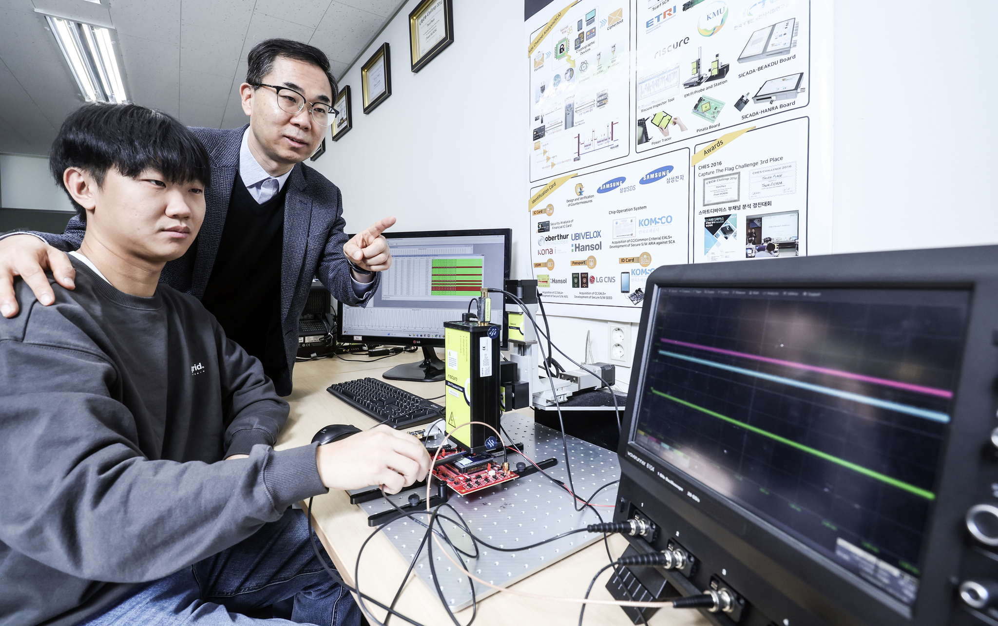 Han Dong-guk, a professor at Kookmin University's Department of Information Security, Cryptography and Mathematics, performs an experiment with a student at the university lab. [JOONGANG ILBO]