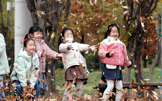 Children from the Buk District local government office workplace daycare center in Gwangju enjoy the colorful late autumn foliage on Thursday at a park commemorating the May 18 Gwangju Democratization Movement at the main gate of Chonnam National University. [NEWS1]