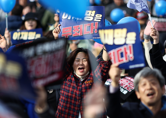 Supporters of Democratic Party leader Lee Jae-myung celebrate outside the Seoul Central District Court in Seocho District, southern Seoul, after the court issued a ruling acquitting Lee of subornation of perjury on Monday afternoon. [YONHAP]