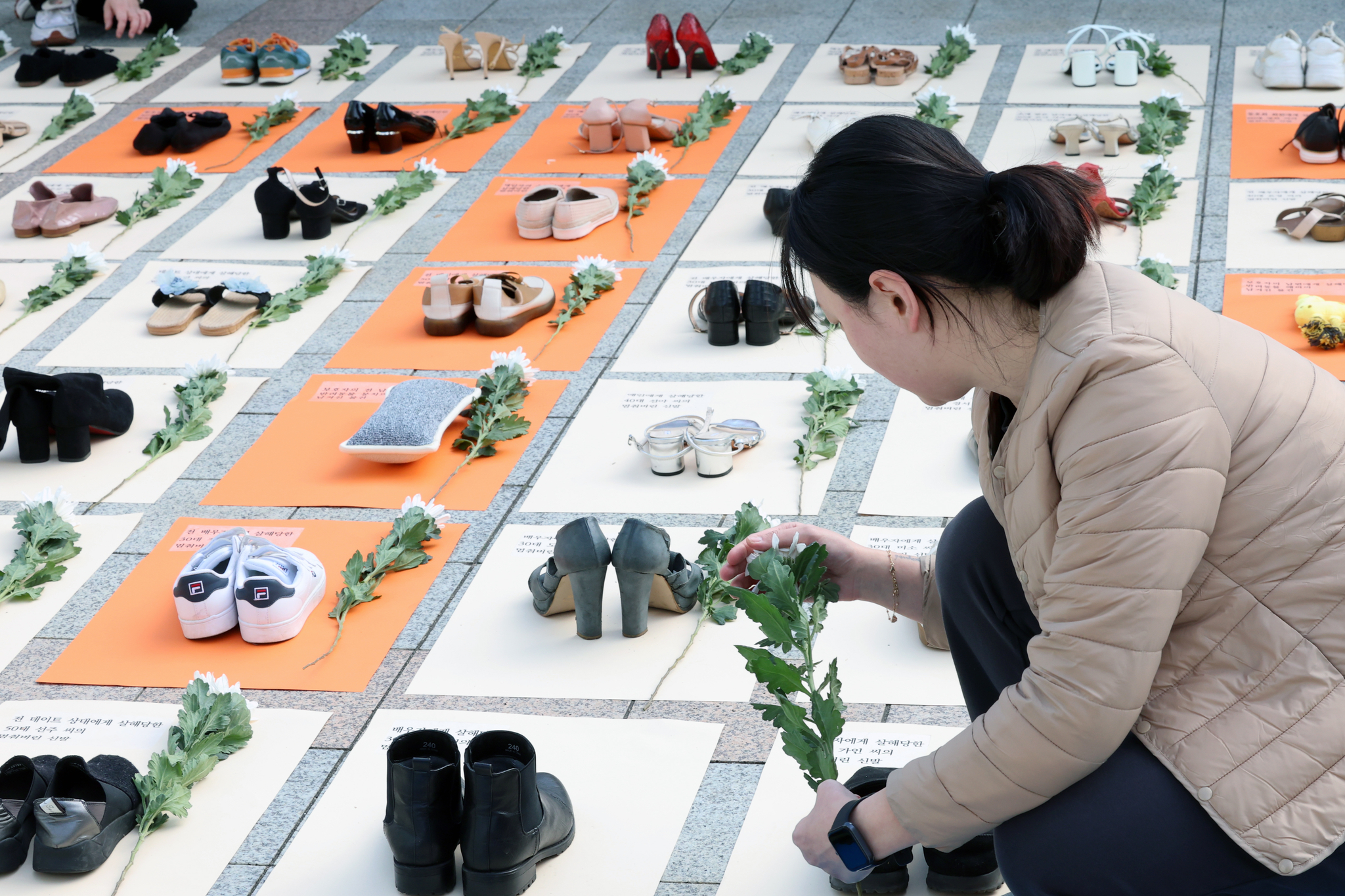 An activist arranges pairs of shoes in front of Bosingak Pavilion in Jongno District, central Seoul, on Monday, which were part of a protest performance conducted by women’s rights activist group Korea Women’s Hot-Line. [NEWS1]