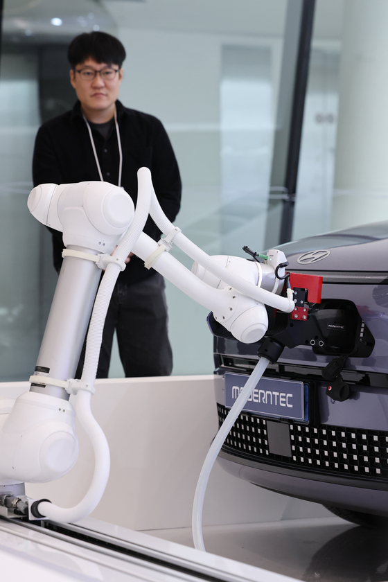 Event officials watch a demonstration of a EV charging robot at the 2024 Seoul Climate Tech Conference in Dongdaemun Design Plaza in Jung District, central Seoul, on Monday. [YONHAP]