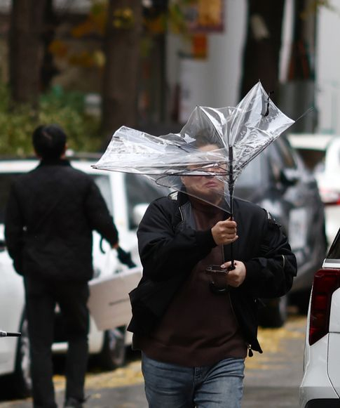 A man struggles to keep his umbrella open against the wind in Mapo District, western Seoul, on Tuesday, when rain fell across much of the country ahead of an expected cold spell. [YONHAP]