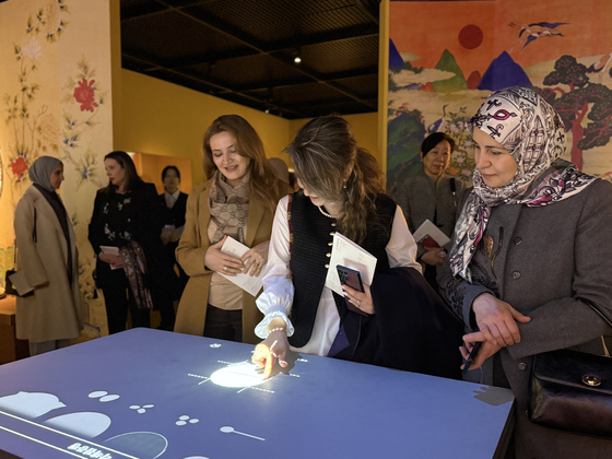 Spouses of foreign ambassadors to Korea build and design their own meal using an interactive display at an exhibition ″Joseon's Royal Cuisine: A Table for Food, Reverence and Sharing″ at the National Palace Museum of Korea in central Seoul on Tuesday. [LEE SOO-JUNG]