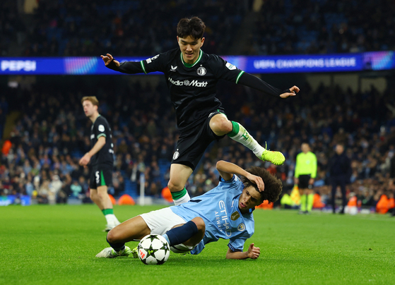 Manchester City's Rico Lewis, front, vies for the ball with Feyenoord midfielder Hwang In-beom during a Champions League match at Etihad Stadium in England on Tuesday. [REUTERS/YONHAP] 